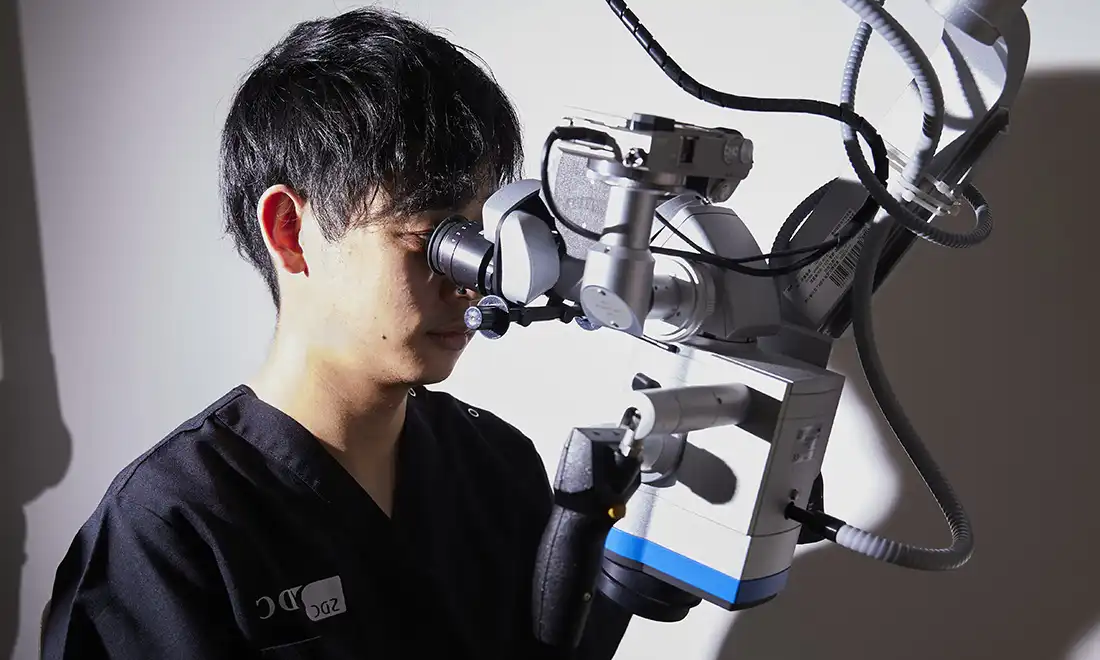 マイクロスコープをのぞき込む歯科医師